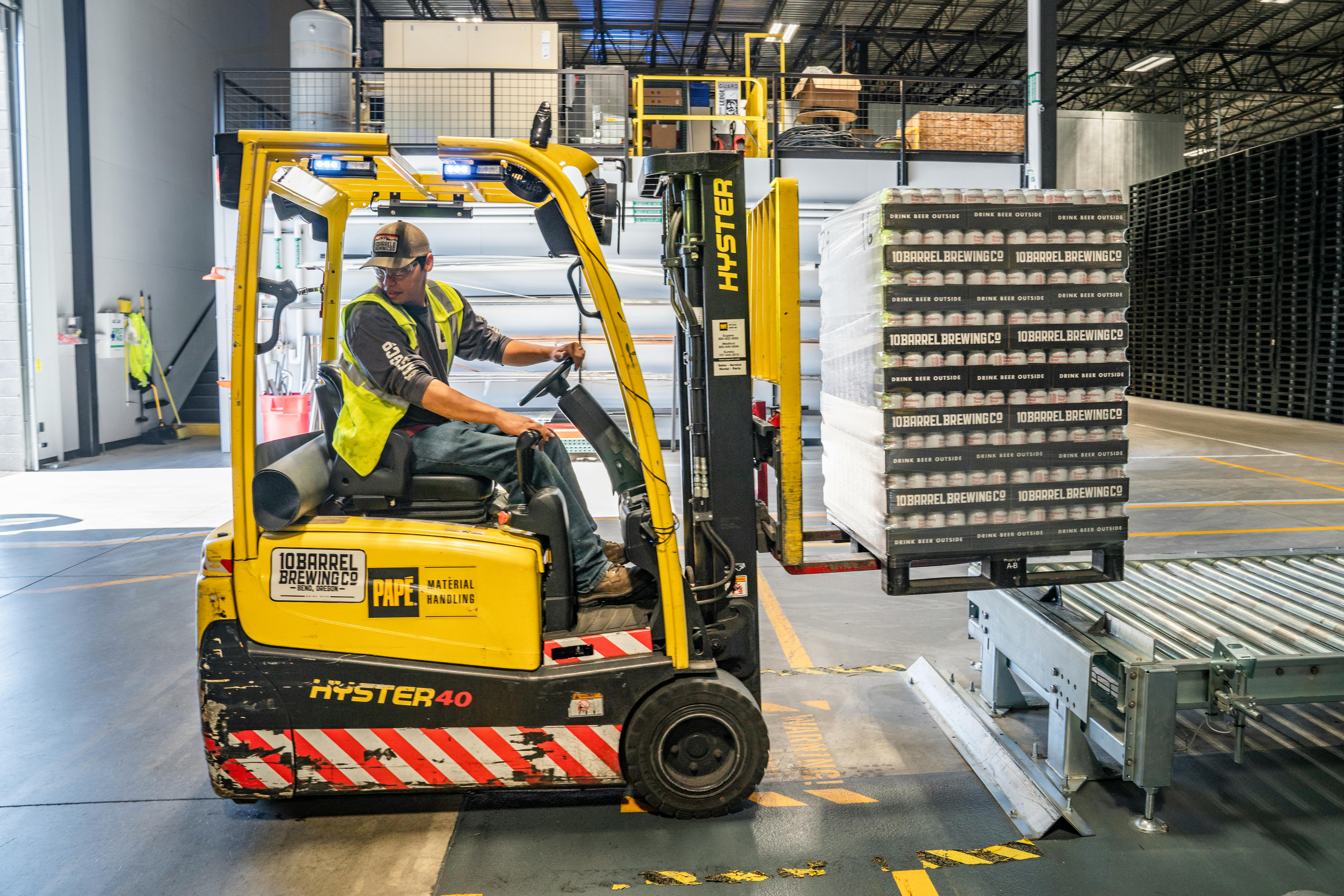 Forklift carrying pallets inside a bright warehouse